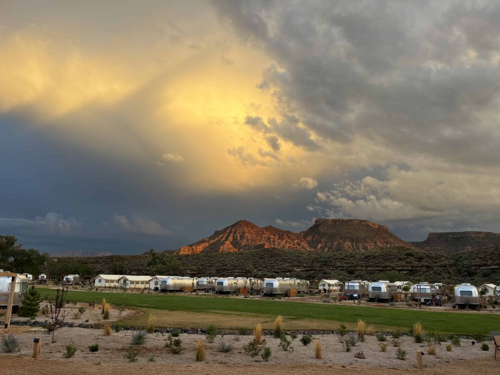 Sun setting in stormy sky over Airstreams at Autocamp Zion