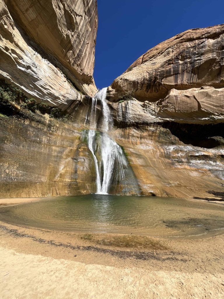 Waterfall with water pooled at bottom against bright blue sky
