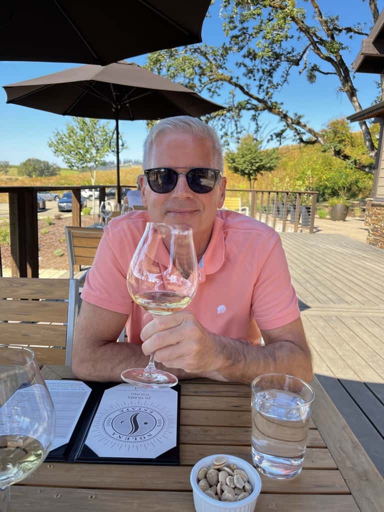 Wine tasting on patio with umbrellas and man holding wine glass
