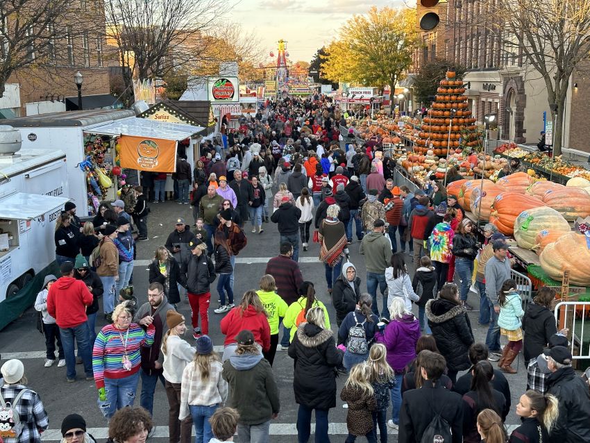 Crowd walking along the midway at the pumpkin show with a tower of pumpkins on the side