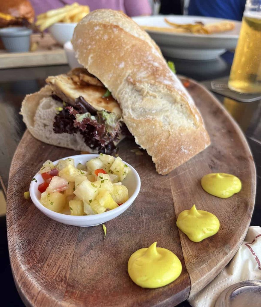 Wooden platter with Caribbean chicken sandwich on it.